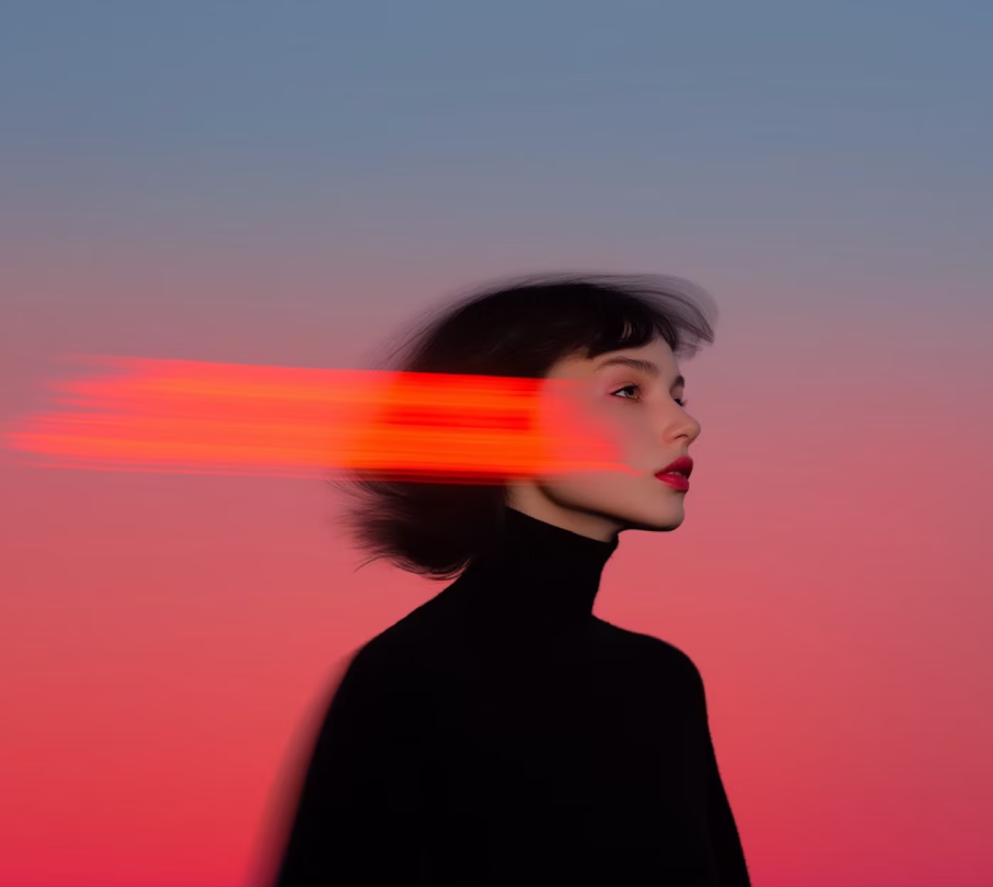 Side profile of a person in a black turtleneck with short dark hair blurred with red light streaks against a gradient pink and blue background.