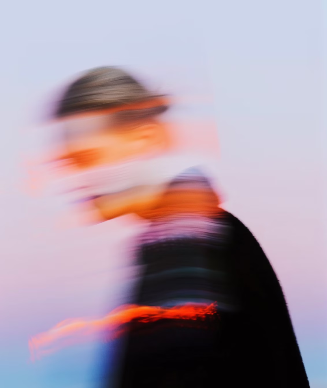 Blurred person in motion wearing dark clothing against a pale sky background.