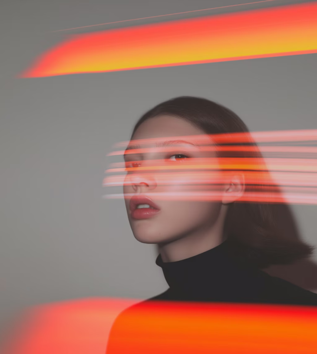 Portrait of a woman with short hair in a black turtleneck, with red and orange light streaks across her face and background.